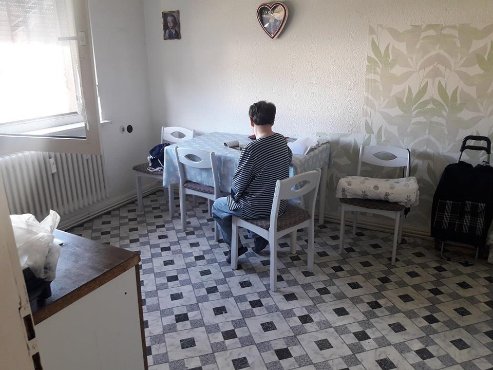 Eine Person sitzt alleine in einem kleinen Raum am Tisch