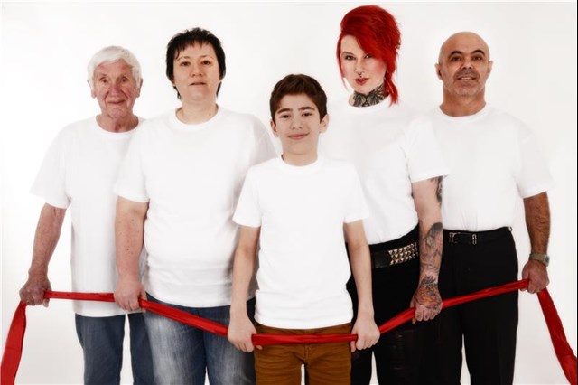 Fünf Personen halten ein rotes Band in der Hand, alle haben ein weißes T-Shirt an