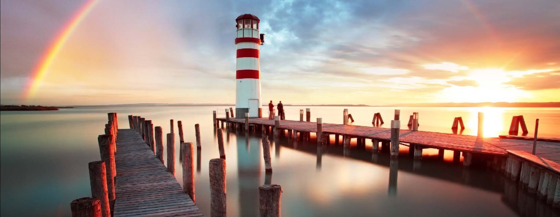 Leuchtturm und Bootssteeg im Sonnenuntergang
